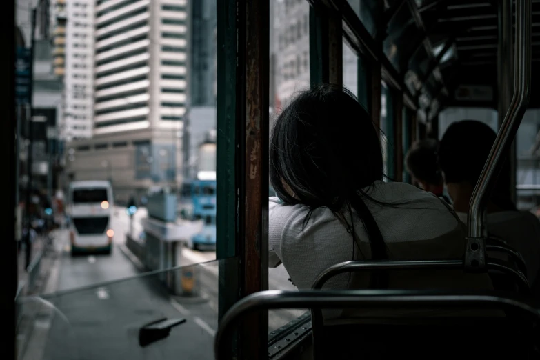 people sitting on the front of a bus as traffic passes by