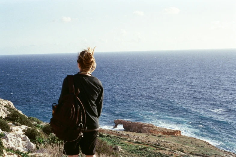 a woman standing on the edge of a cliff next to the ocean