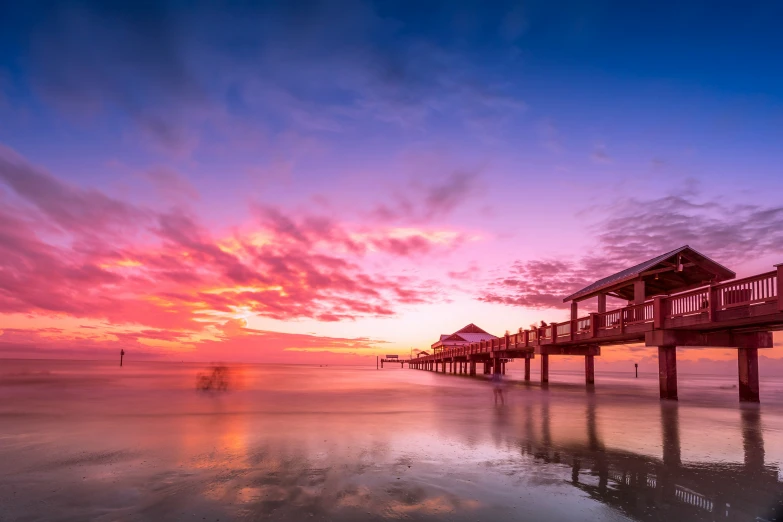 a dock is next to a small house with a sunset in the background