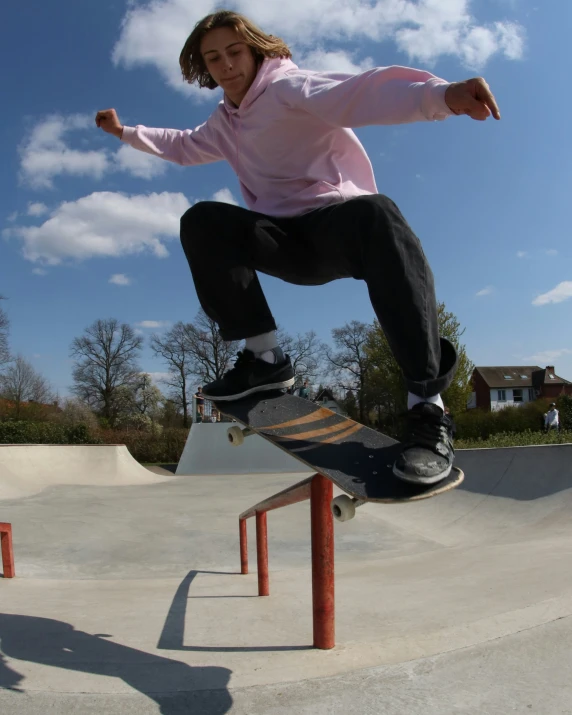 a girl jumping her skateboard over a metal rail