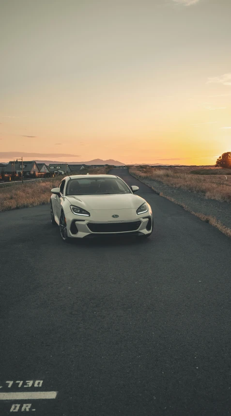 a white sports car driving on a road during sunset