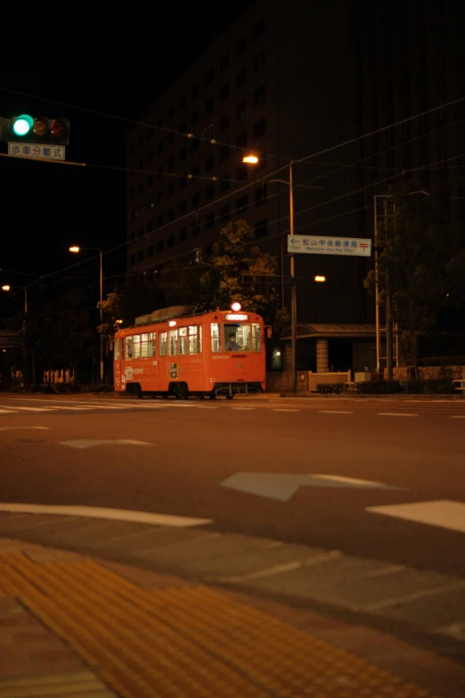 a red bus is driving by a traffic light