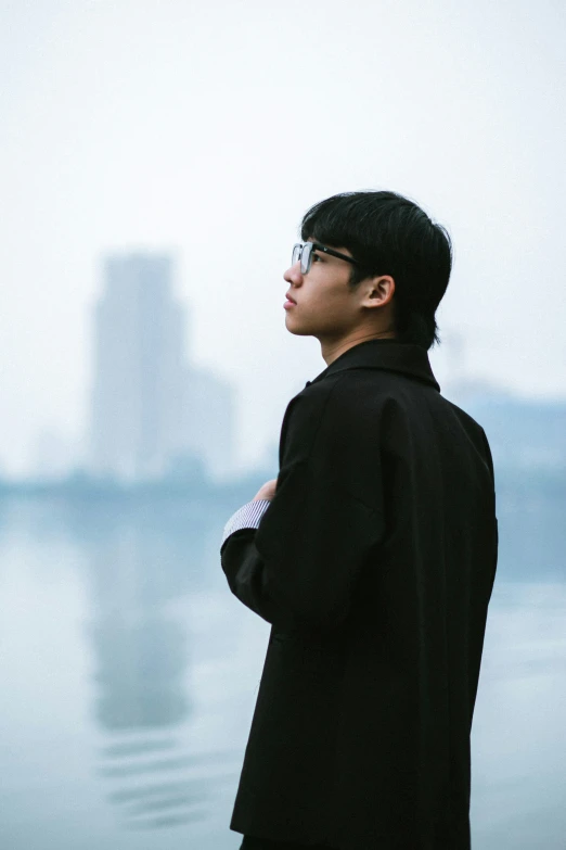 an asian male is standing next to a body of water