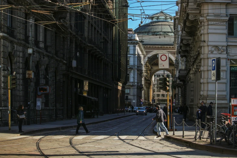 a couple of people walking down a street next to a train track