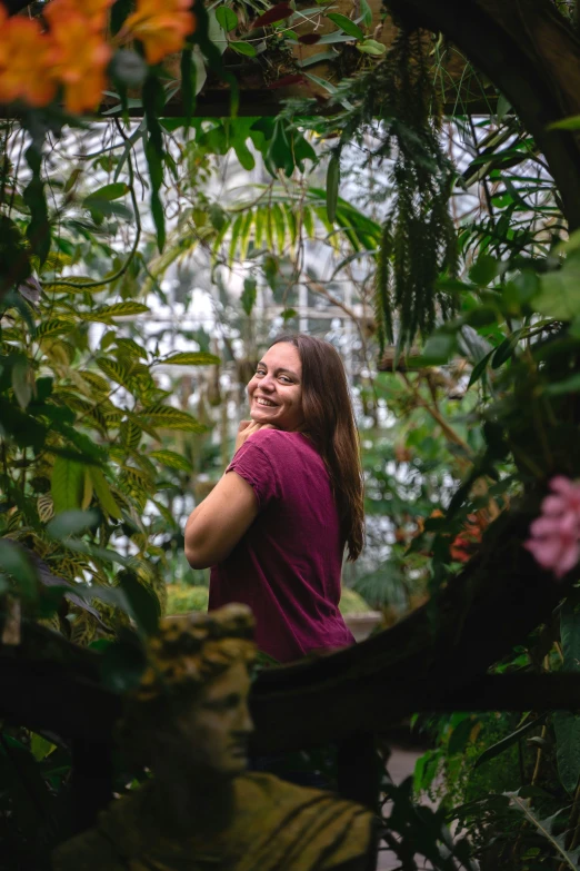 a smiling young lady sitting in some bushes