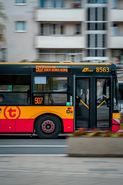 an orange and red bus driving down the street