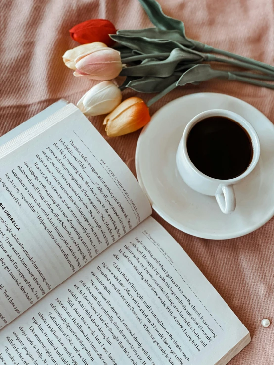 a close up of a book, cup of coffee and flowers