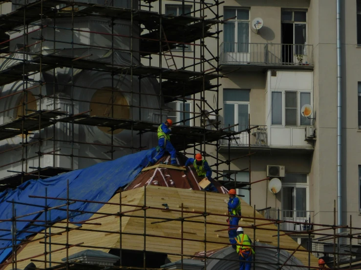 construction workers working on a roof with scaffolding in the background