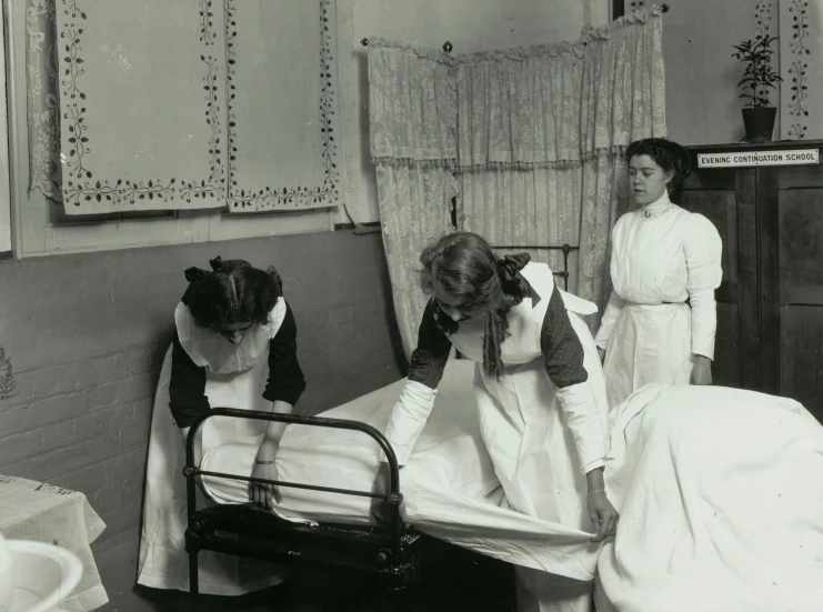 women in colonial garb holding the rails of a hospital bed
