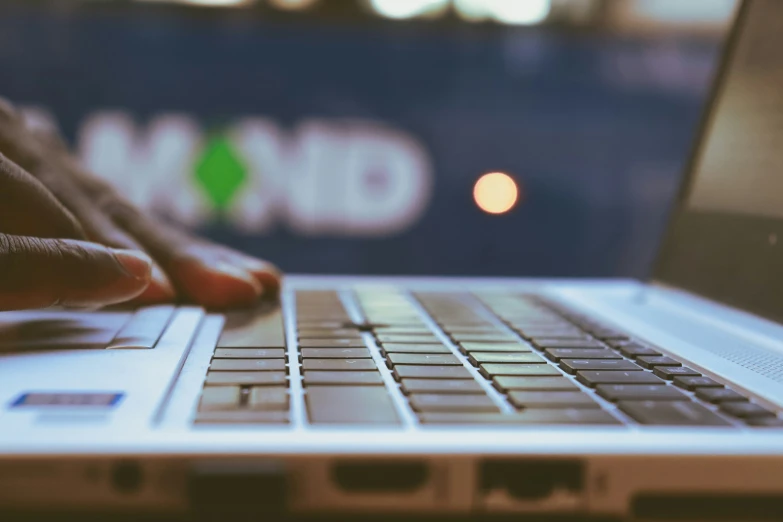 a laptop with one hand resting on the keyboard