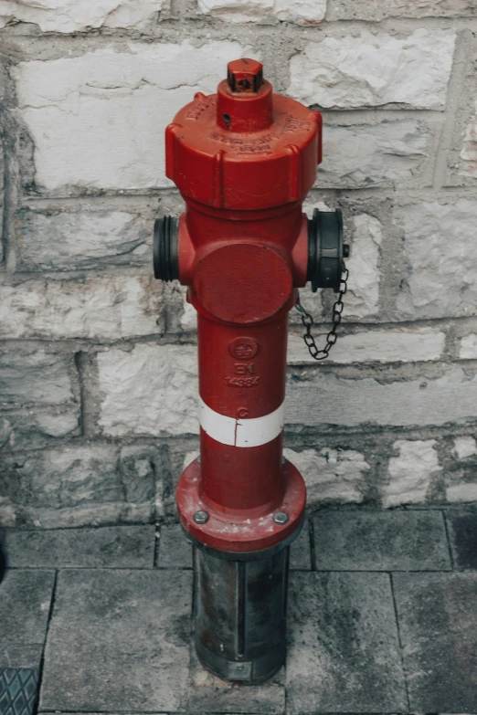 a red and white fire hydrant next to a brick wall