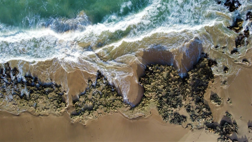 a sea wave cresting towards the beach, looking down