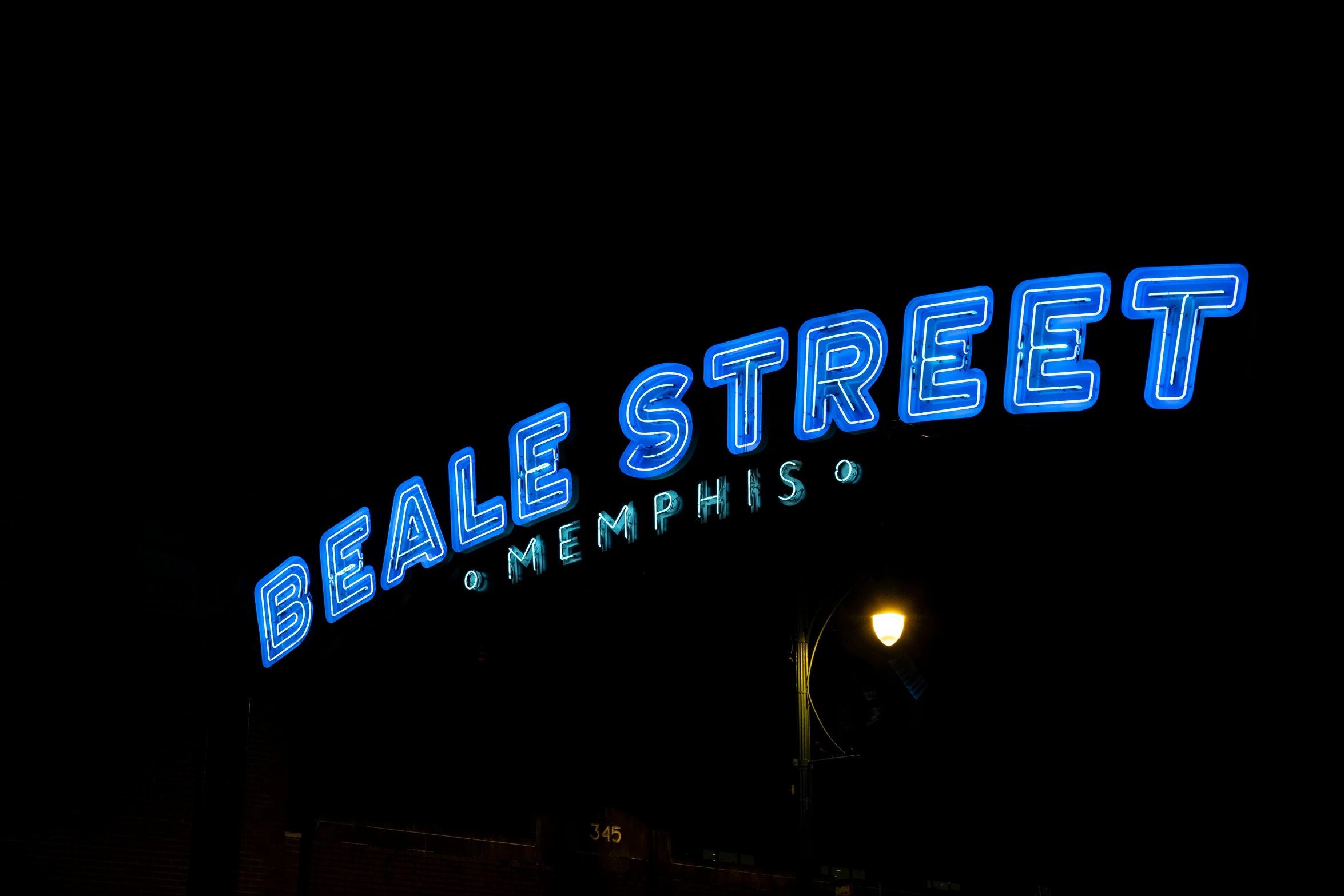 blue neon sign above the entrance to a dark street