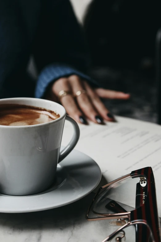 the woman is holding her hands over the cappuccino