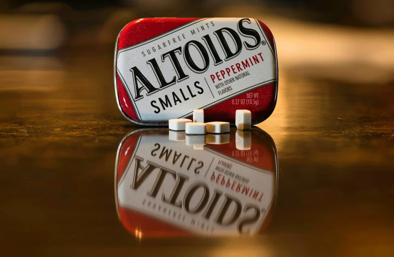 an old red packet of altoids on top of a wooden table