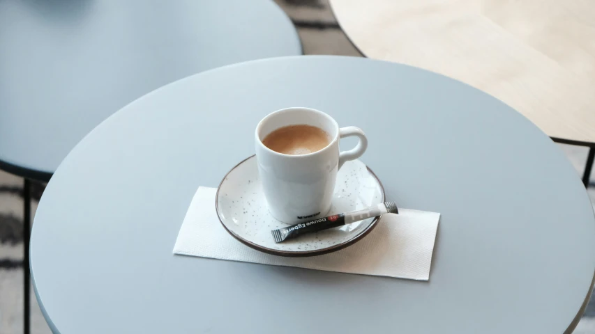 a cup with a spoon on a saucer near some chairs