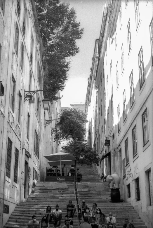 several people are sitting on the steps in an alley