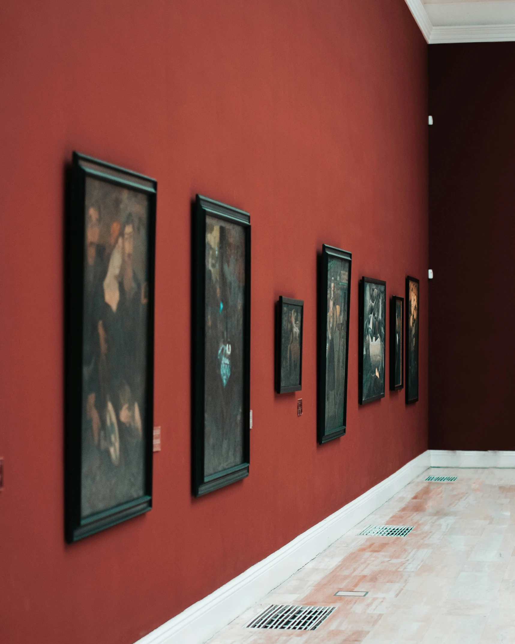 red room with paintings hanging on wall, and white floor