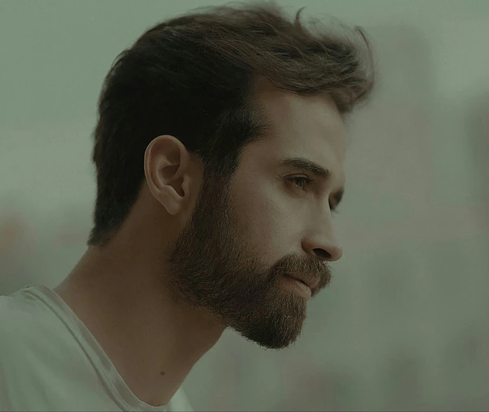 a bearded man is standing in front of a white wall