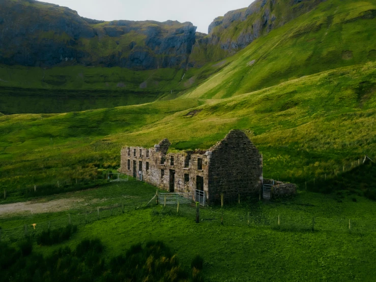 a old abandoned building in the middle of a green valley