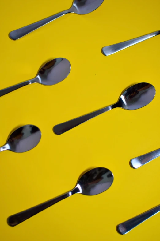 six spoons arranged in a line on a yellow surface