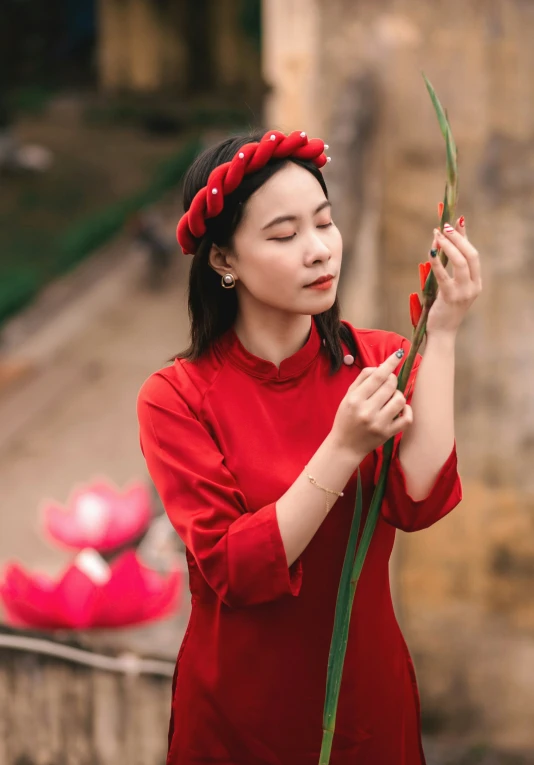 a woman wearing a red top holding a flower