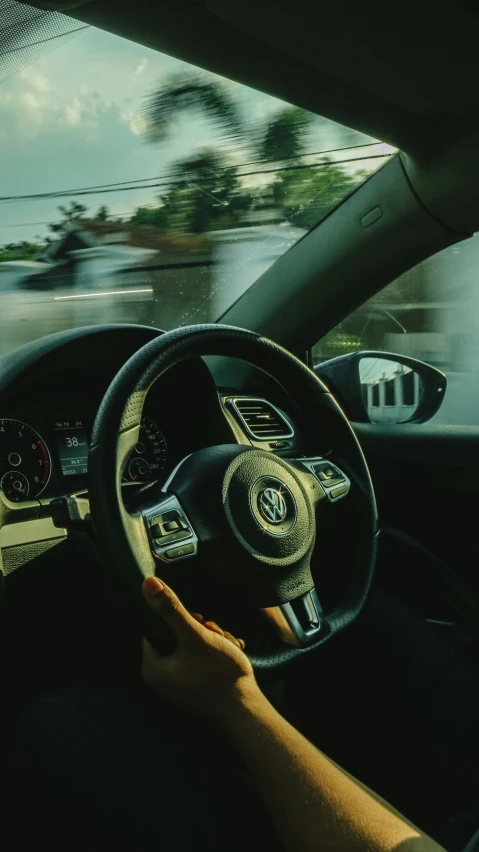 someone holding the steering wheel of a car while driving