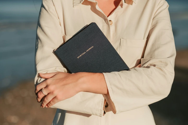 a woman wearing a white dress holding a large bible