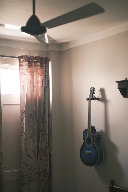 guitar resting on wall next to window in dark room