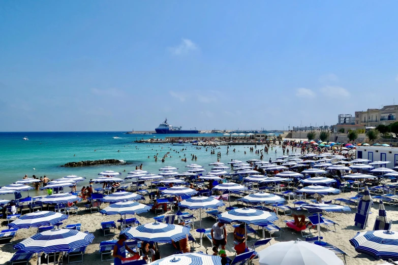 a bunch of blue umbrellas in the shade on a beach