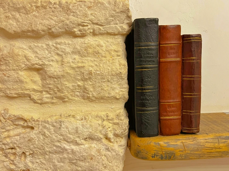 a bookshelf with three old books sitting next to it