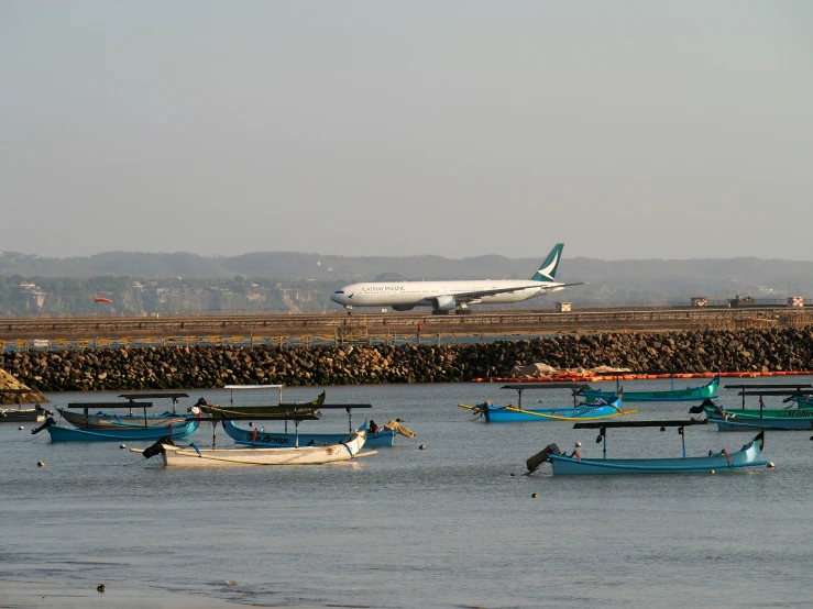 there are several boats and an airplane flying over the water