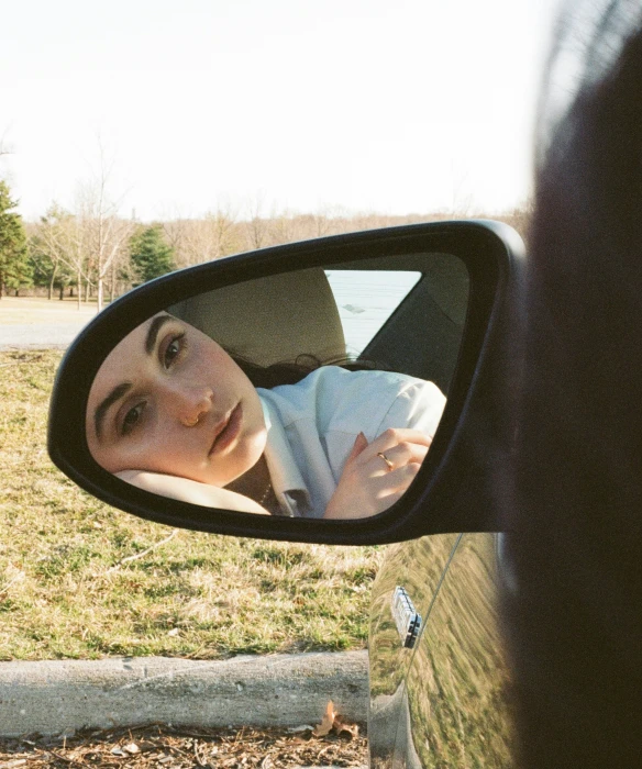 a woman taking a picture in the rear view mirror