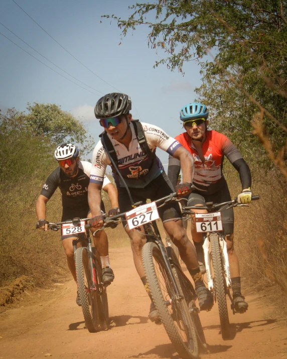 three men wearing helmets and bike gear racing bikes