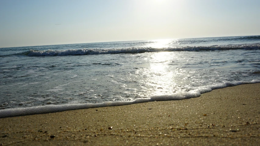 a beach area with the sun reflecting on the water