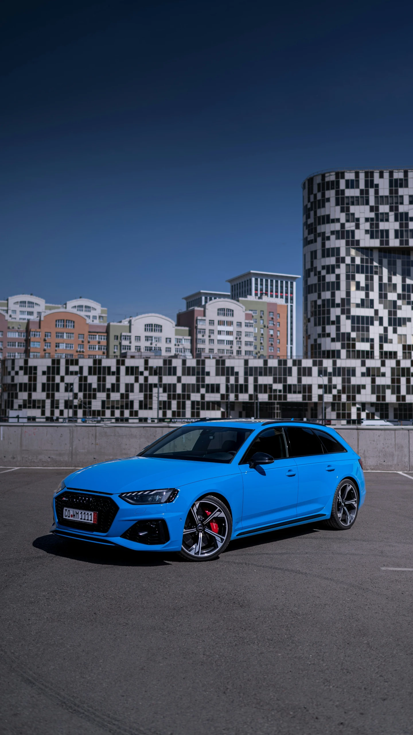 a blue car in an empty lot near buildings