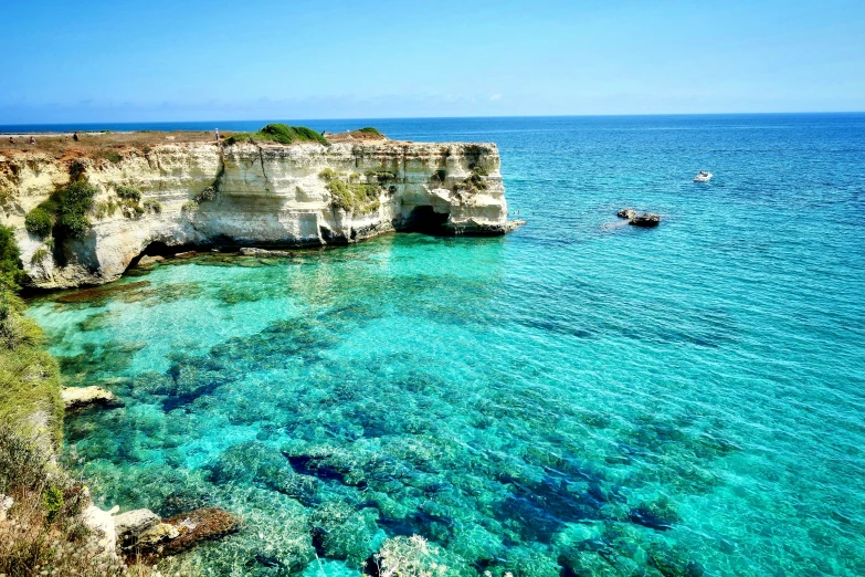 the ocean, with cliffs and boats, appears to be surrounded by sandy terrain