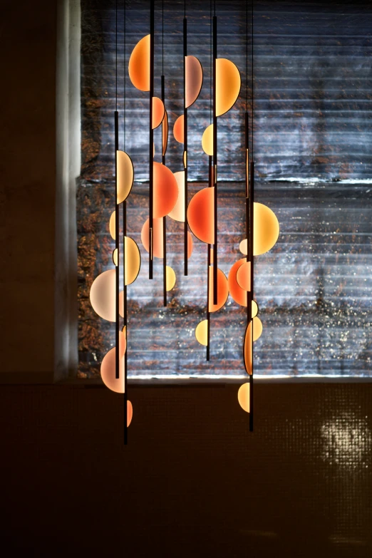 a multi light fixture with a bunch of orange glass circles hanging from it's center