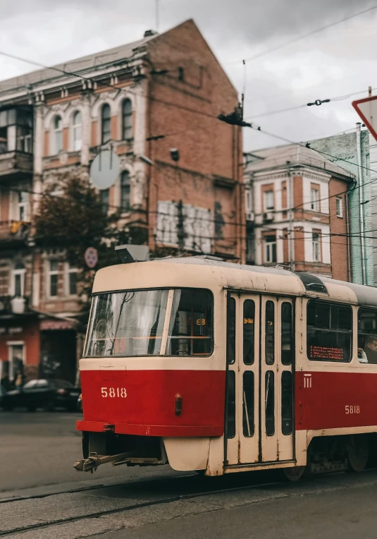 a white and red trolley in a street in front of a large building