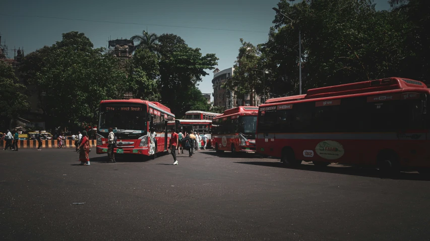 a couple red buses are next to each other