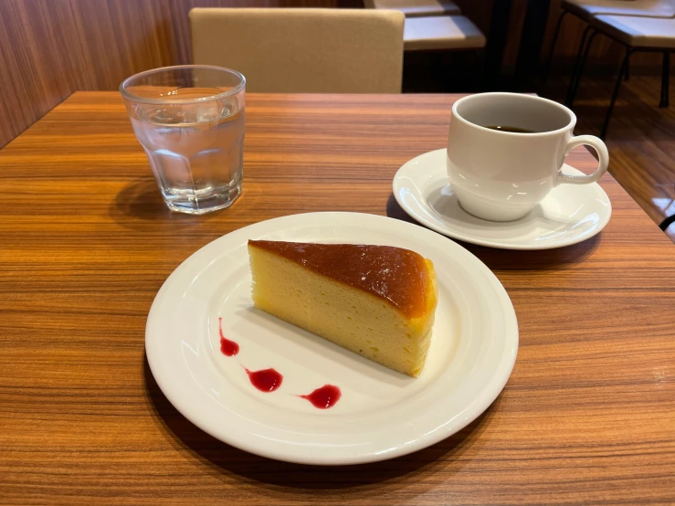 a piece of cake is on a plate next to a glass of water