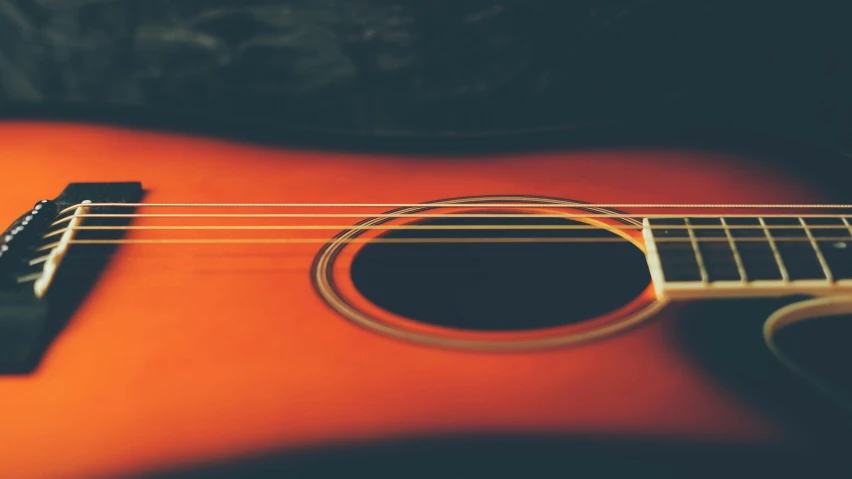 a red guitar sitting on top of a black surface