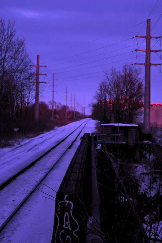 the view of a snowy train track during twilight