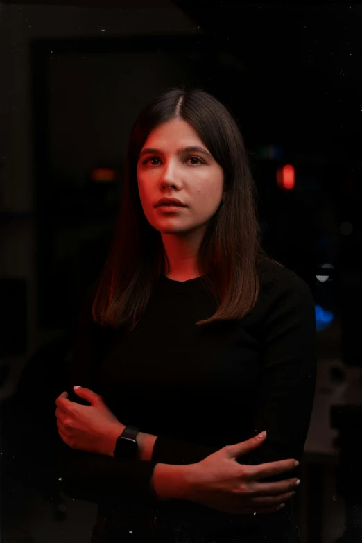 a woman standing in a dark room with her arms folded