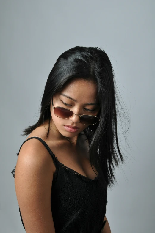woman with long dark hair and brown sunglasses holding a phone