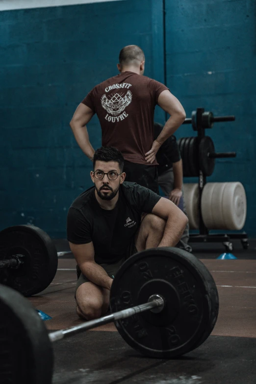 a man squats down with a barbell in his hand