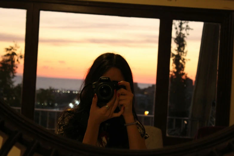 a woman taking a picture through a mirror with her camera