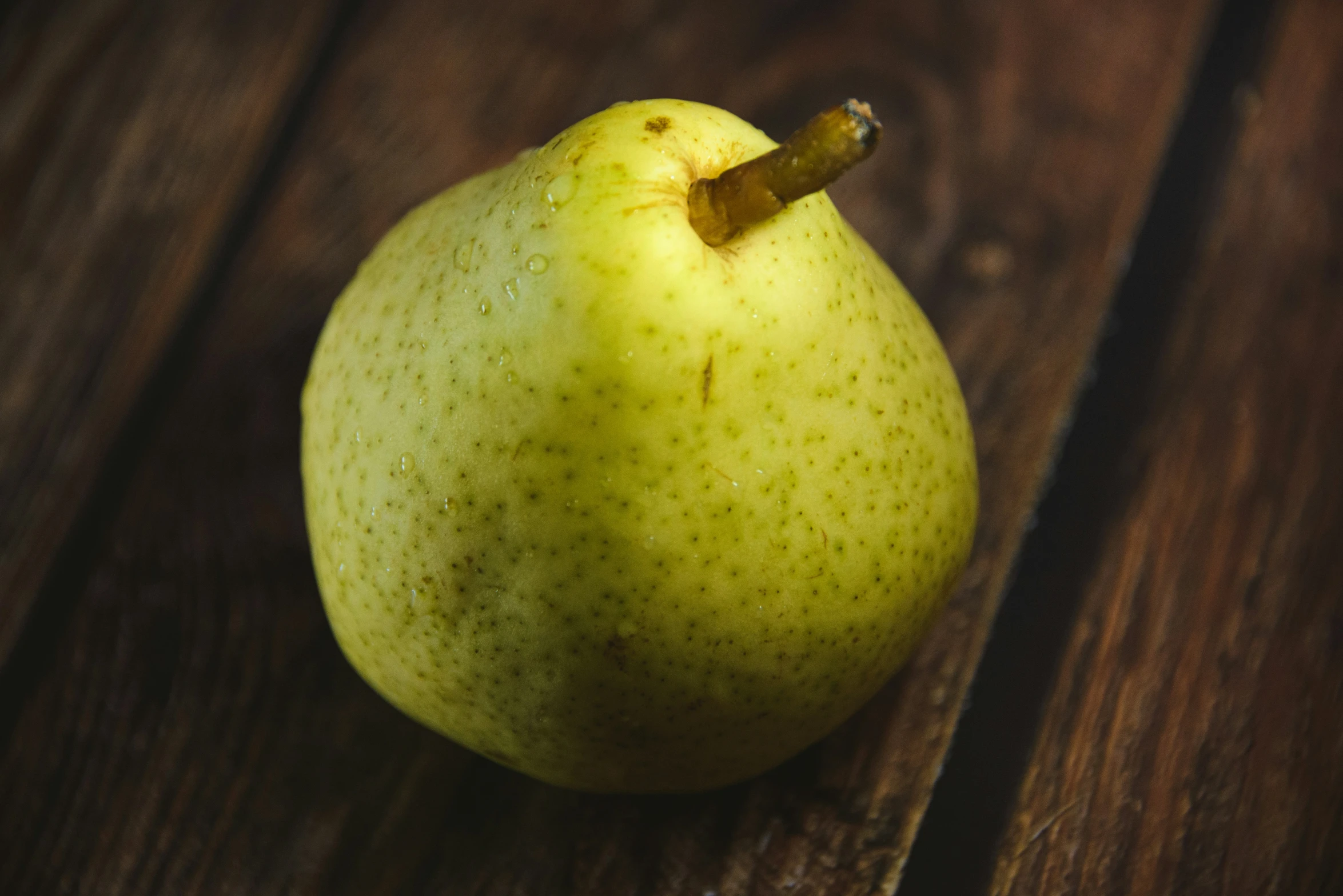 a yellow pear sitting on top of a wooden table