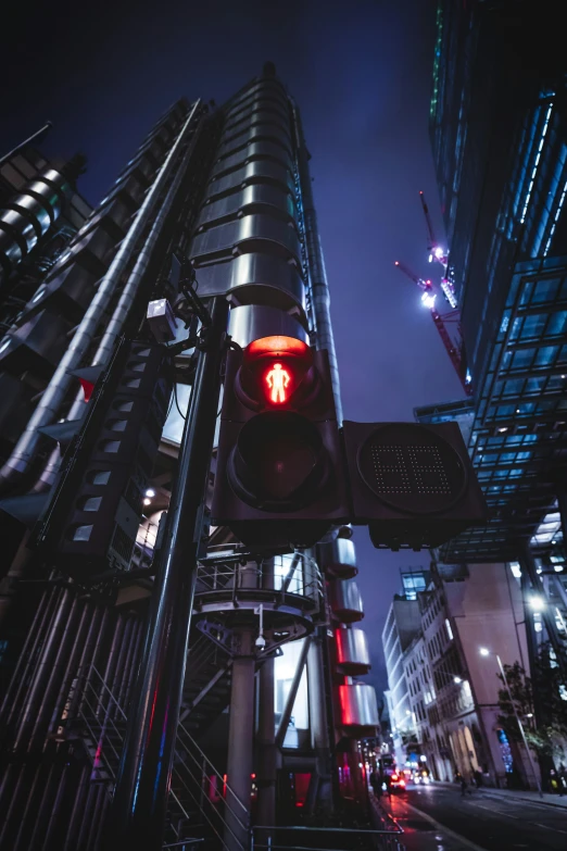 a red stop light with a street sign near a skyscr