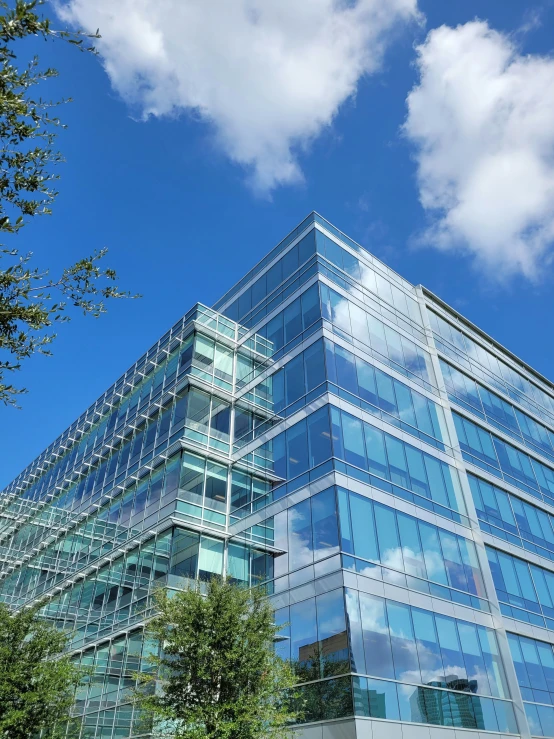 an office building with large glass windows and trees